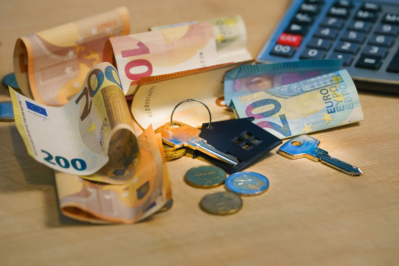 Model domu, mince a kalkulačka jako symbol výpočtu daně z nemovitosti